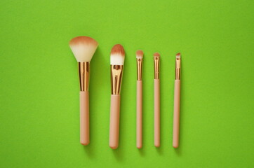Set of makeup brushes on a green pastel background. Top view point, flat lay. Beauty and trend life style concept.