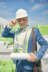 Smiling engineer holding drawings in his hand