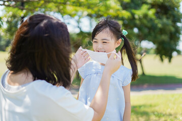 Naklejka premium 子どもにマスクを付けさせるお母さん