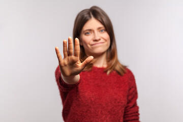 Prohibition concept. Portrait of girl in shaggy sweater stretching out hand, warning with stop...