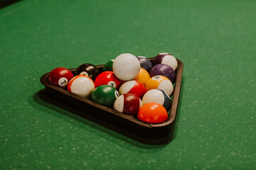 Billiard's balls laying together on a green pool table.