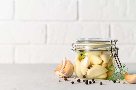 Healthy fermented food. Homemade fermented garlic with dill and pepper in a glass jar. Light background. Copy space.
