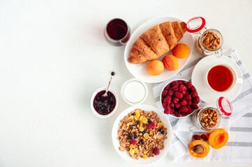Light summer breakfast with muesli, milk, juice, apricots and raspberries on a light background. Flatly.