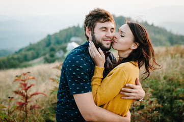 Couple travelers. Man and woman kissing on the background on mountains. Love and travel, happy emotions. Lifestyle concept. Portrait of a happy couple laughing at camera.