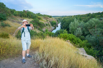 guy takes a selfie while traveling through the canyon. Guy with a backpack and a blue t-shirt
