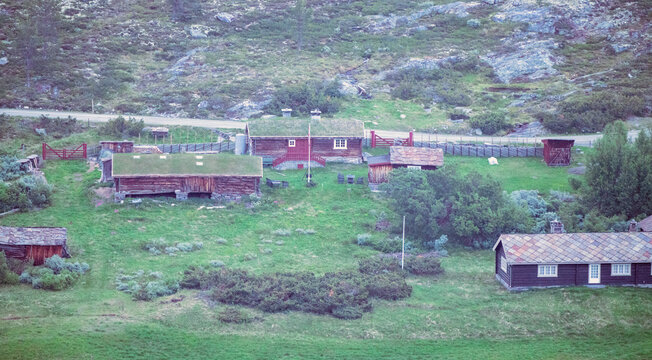 Old and rustic wooden cabins outdoors in the Norwegian mountains. Shot from above, high angle. During blue hour.