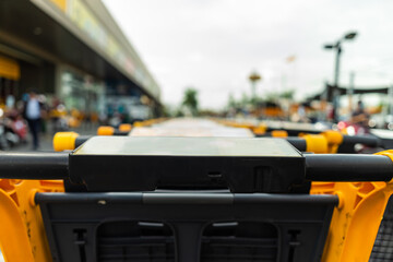 Row of yellow shopping carts at supermarket entrance with blur and bokeh lights background.