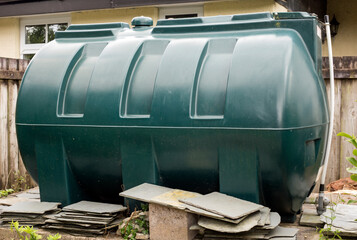 A green plastic fuel oil tank in a rural garden in Cornwall, England