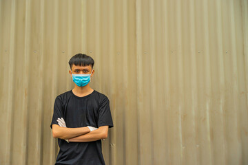 Asian young man wearing a protective hygiene mask over her face to protect flu and virus. Unwell influenza in infected man portrait with light brown background