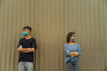 Asian young couple wearing a protective hygiene mask over her face to protect flu and virus. Unwell influenza in infected cpuple with light brown background.