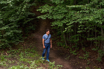 Naklejka na ściany i meble Adult man hiking in the forest in summer