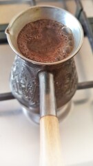 Coffee is brewed in Turk. Hot foam rises up.