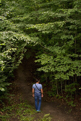 Naklejka na ściany i meble Adult man walking through the forest in summer