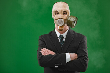 Portrait of a man wearing a business suit and an old gas mask, isolated on green background with fog.