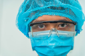 Closeup portrait of a mature male surgeon in the operating room, Male medical worker with medical mask looking seriously to camera, space for text, selective focus.