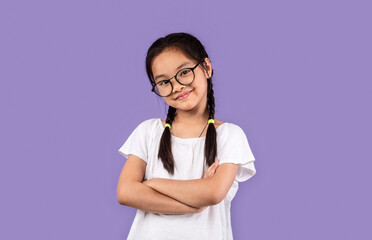 Little Chinese Girl Wearing Eyeglasses Posing Crossing Hands, Purple Background