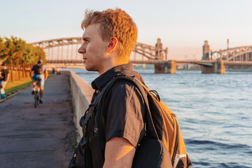 Fototapeta premium Business man programmer blond in a shirt on the background of Bolsheokhtinsky bridge at sunset in St. Petersburg