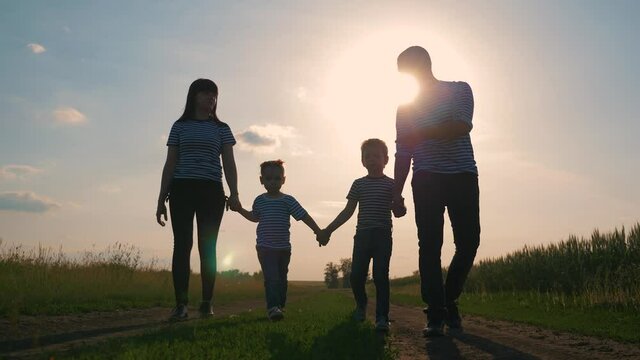 Happy family. Lovely couple with kids strolling at sunset in the evening around the field. The concept is the teamwork of hiking, active lifestyle, parenting.