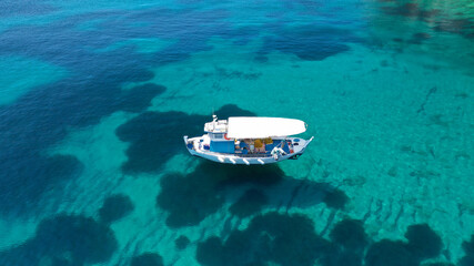 Aerial drone photo of beautiful fishing boat anchored in turquoise sea of Stafilos bay, Skopelos island, Sporades, Greece