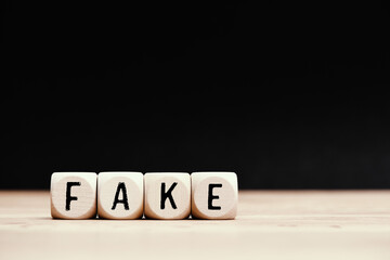 Social topic "Fake" written on wooden cubes with dark background