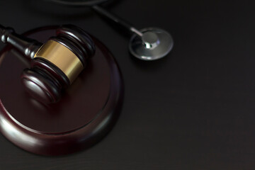 Judge's gavel and medical stethoscope on black wooden table with copy space