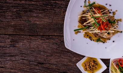 Steam fish with soy sauce is a clean food for good health. Presents in a close up on wooden background.