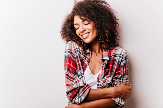 Photo of sensual young african woman. Amazing brunette girl in red checkered shirt laughing with eyes closed.