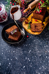 Chocolate Gingerbread Cake on festive background. Traditional Gingerbread cake with dark chocolate topping, cranberry and rosemary, on Christmas decorated table, copy space
