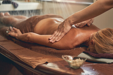 Gentle female hands massaging back of client