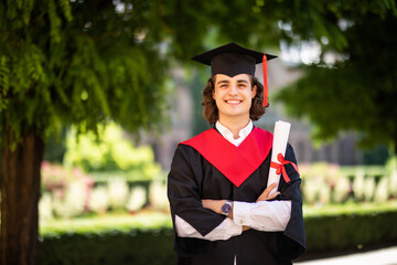 Graduation of student standing with diploma with friends behind