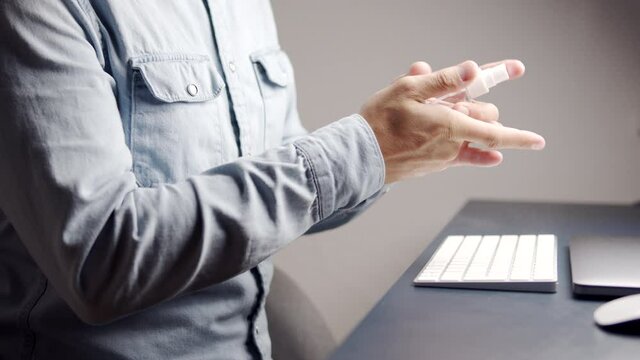 Male sanitizes hands at the workspace 
