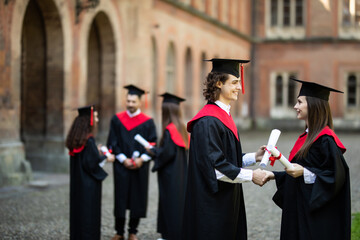 Education, graduation and people concept. Group of happy international students in mortar boards and bachelor gowns with diplomas