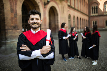 Smiling graduate smiling with her friends in background in front of the university