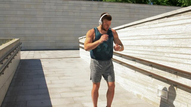 fitness, sport, training and lifestyle concept - young man in headphones running outdoors