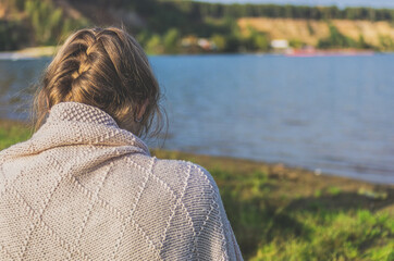 Back view of woman in knitted clothes with gathered bun of hair on the background of the lake