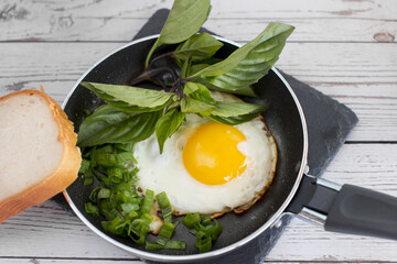 fried Eggs in a frying pan and a piece of white bread. Drink fresh milk for Breakfast decorated with a pink flower.