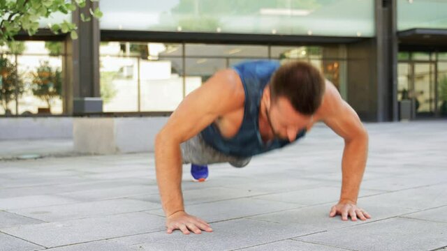 fitness, sport and training concept - young man doing push ups on city street