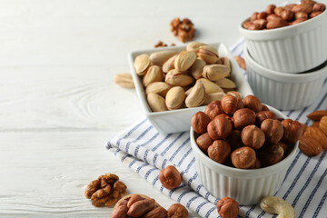 Bowls with different nuts on white wooden background. Vitamin food