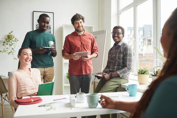 Obraz premium Portrait of cheerful multi-ethnic team talking to boss or manager during business meeting in office, copy space