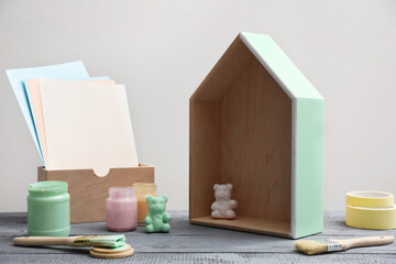 Brush with paint and model of house on grey wooden table
