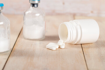 Various pill bottles and different pills on wooden table