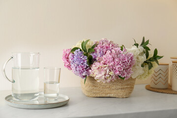 Beautiful hydrangea flowers in basket and water on light table