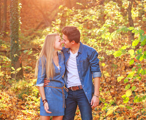 Young couple in love together in happy embrace in autumn forest, in rays of setting sun