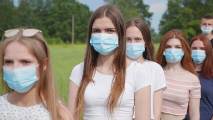 Pandemic concept. A group of students stand in a row in masks.
