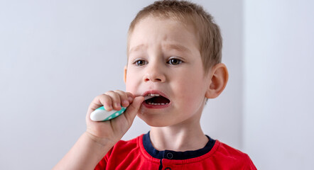 A little boy is learning to brush his teeth using a toothbrush. Concept of child hygiene and independence