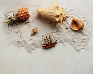 Obraz premium Summer tropical concept on a beige background. Background with seashells different shape and type in the sand. Pineapple. Sailing ship. Top view, copy space