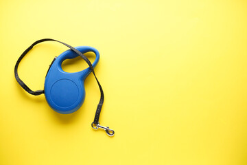Blue retractable dog leash on a yellow background, with space for text. Flat lay.