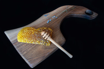 Raw honeycomb on cutting board. Black background,copy space, natural product