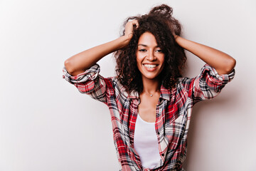 Fascinating african lady with happy face expression playing with her short hair. Studio portrait of glad black girl isolated on white background.