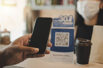 customer hand using digital mobile phone scan QR code pay for buying coffee in modern cafe coffee shop, cafe restaurant, digital payment, online shopping, takeaway food, internet technology concept